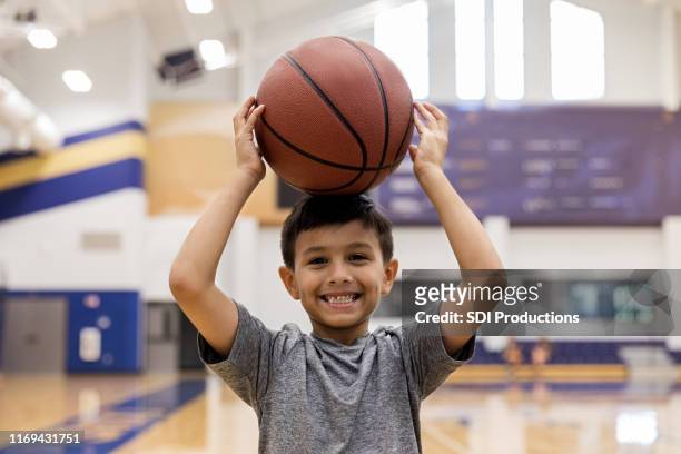 elementary age boy goofs off with basketball for camera - basketball sport stock pictures, royalty-free photos & images