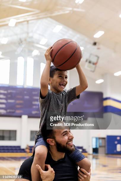 with nephew on uncle's shoulders, both have fun shooting baskets - family vertical stock pictures, royalty-free photos & images