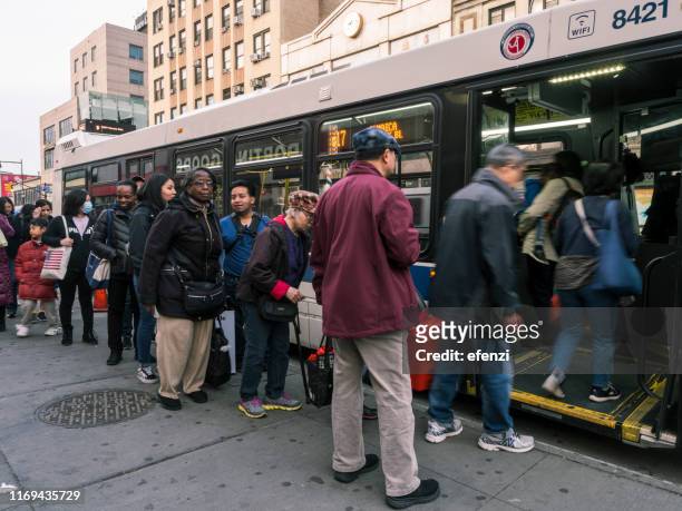 persone in coda per arrivare in autobus - flushing queens new york foto e immagini stock