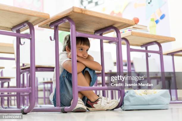 shy kid hiding under table - rougir photos et images de collection