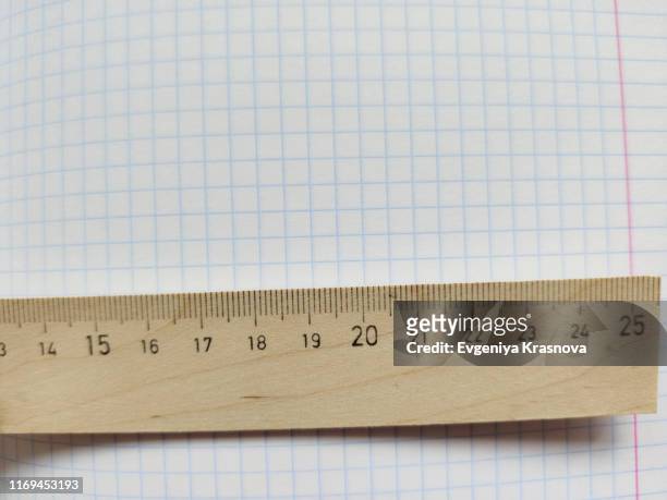 wooden ruler with metric system rests on a white checkered exercise book without notes - workbook stockfoto's en -beelden