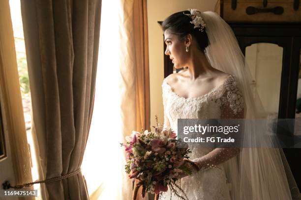 bride holding bouquet and looking through the window - nervous bride stock pictures, royalty-free photos & images