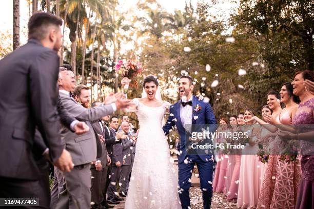 confettis jetant sur le couple heureux de jeunes mariés - cérémonie du mariage photos et images de collection