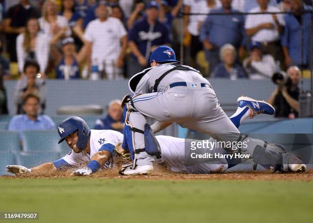 Chris Taylor of the Los Angeles Dodgers reacts as he is tagged out by Reese McGuire of the Toronto Blue Jays, attempting to stretch a triple into an...