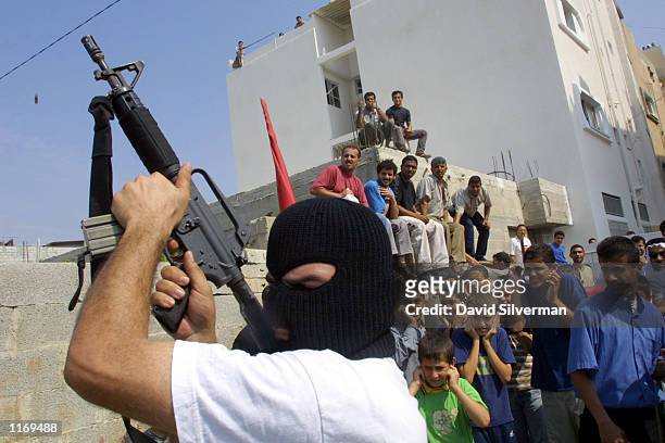 Masked Palestinian gunmen fire their weapons in the air during the funeral of Hamas militant Abdel Rahman Hamad October 14, 2001 in the West Bank...