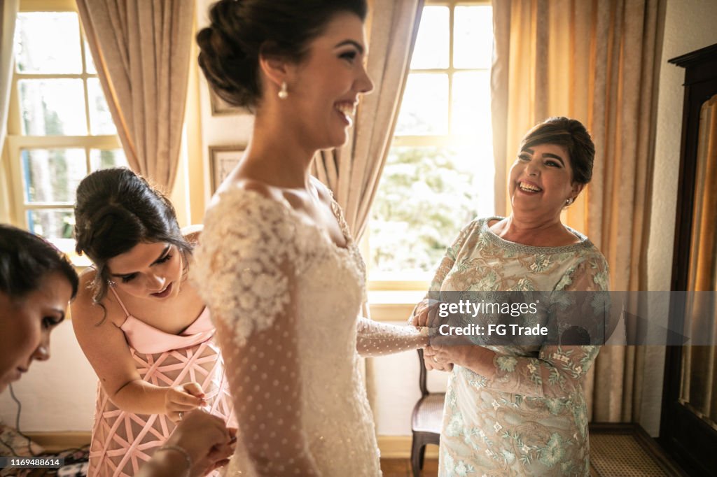 Damigelle che aiutano la sposa a vestirsi per la cerimonia nuziale