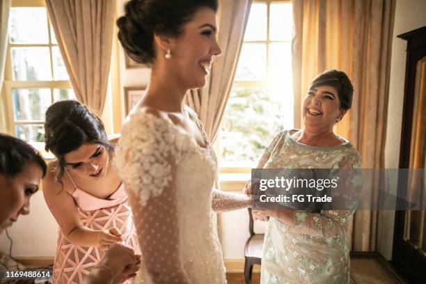 bridesmaids helping bride getting dressed for the wedding ceremony - getting ready stock pictures, royalty-free photos & images