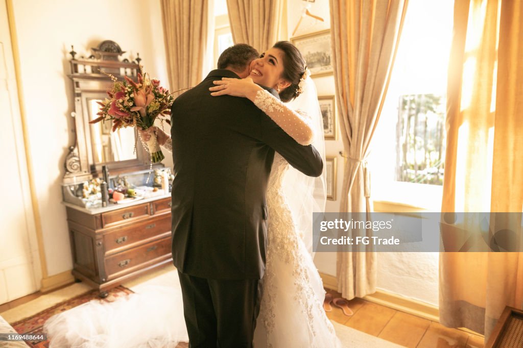 Bride and father embracing before wedding ceremony