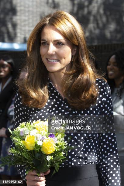 Britain's Catherine, Duchess of Cambridge carries a posy as she leaves after her visit to the Sunshine House Children and Young People's Health and...