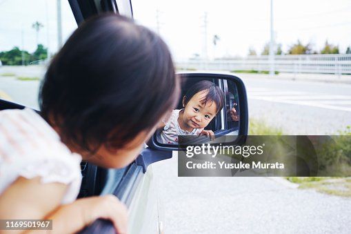 Portrait of little girl in side-view mirror of car