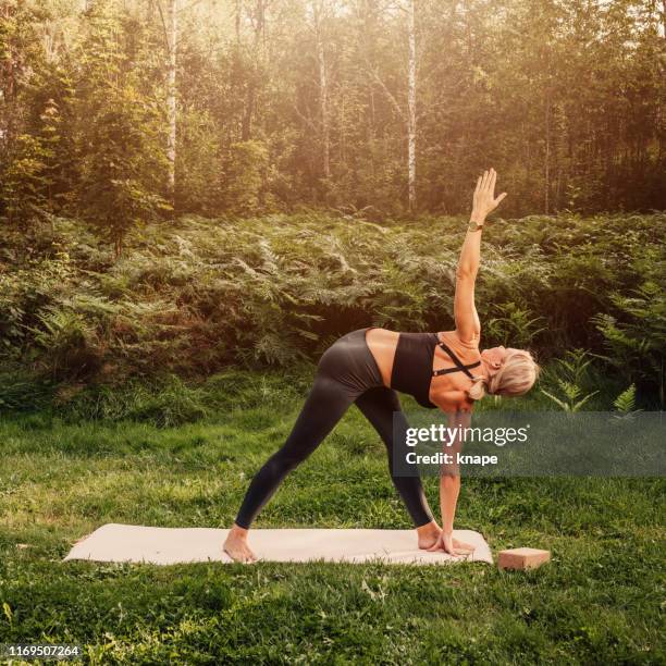 normal mid adult woman doing yoga series -parivrtta trikonasana - parivrtta trikonasana stock pictures, royalty-free photos & images