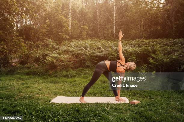 normal mid adult woman doing yoga series -parivrtta trikonasana - parivrtta trikonasana stock pictures, royalty-free photos & images