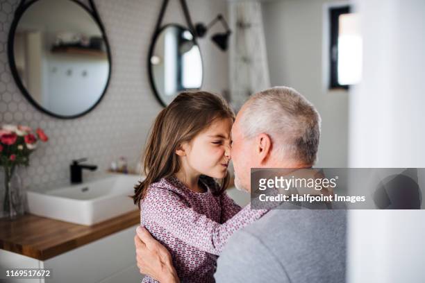 senior grandfather and granddaughter sitting indoors in bathroom, talking. - senioren in bad stock-fotos und bilder