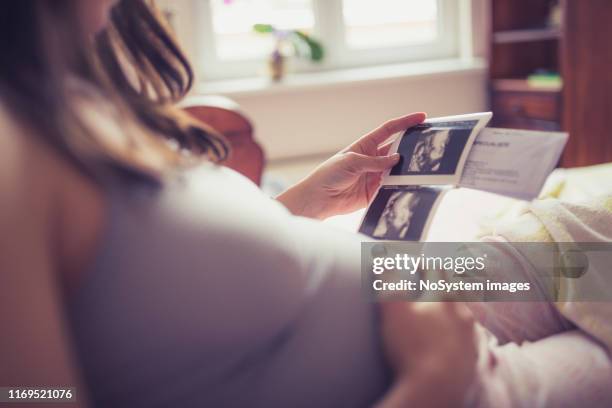 joven mujer embarazada examinando su ultrasonido - ecografía fotografías e imágenes de stock