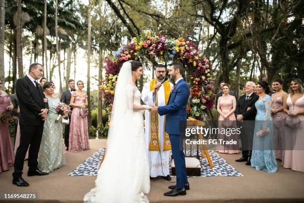 vue de côté du marié et de la mariée dans l'autel - cérémonie du mariage photos et images de collection