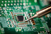 Soldering a micro chip processor with iron tool green circuit boad. Electroncs service technology and macro computer concept background.