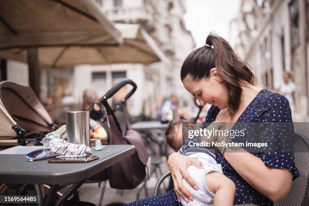 young mother breastfeeding her baby boy in public place - public building stock pictures, royalty-free photos & images