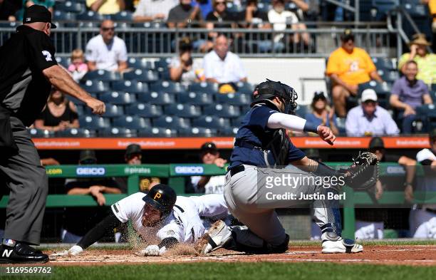 Joe Musgrove of the Pittsburgh Pirates slides safely past Omar Narvaez of the Seattle Mariners to score a run on a RBI single by Kevin Newman in the...