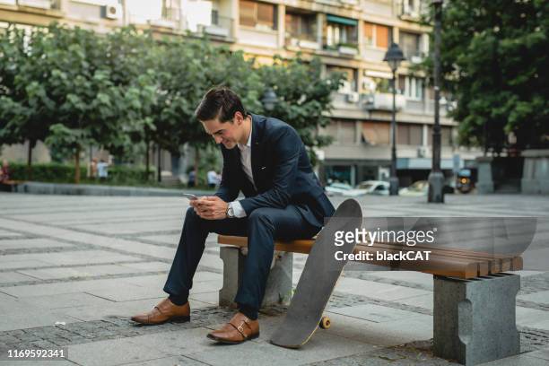 affärsman sitter på en bänk bredvid skateboard - suave bildbanksfoton och bilder