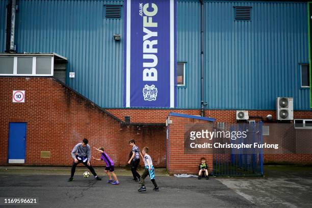 Youngters play football outside Gigg Lane stadium the home of struggling football club Bury FC on August 22, 2019 in Bury, England. Bury Football...