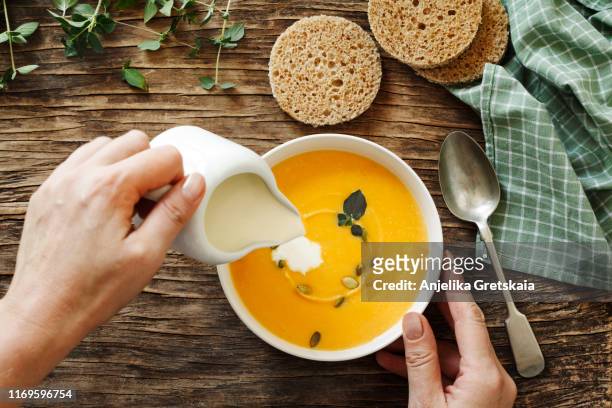 pumpkin creamy soup on dark wooden background - spoon in hand stock pictures, royalty-free photos & images