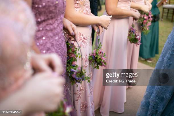 niedriger abschnitt der brautjungfer hält blumen während der hochzeitszeremonie - bridesmaid dress stock-fotos und bilder
