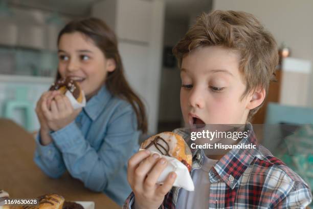 fratello e sorella affamati a casa che si godono le ciambelle - fat people eating donuts foto e immagini stock