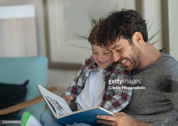 loving daddy and son reading a book together having fun laughing - reading stock pictures, royalty-free photos & images