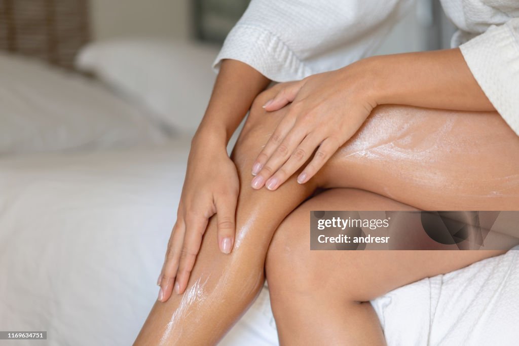 Close-up on a woman applying cream on her legs