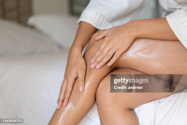 close-up on a woman applying cream on her legs - woman body imagens e fotografias de stock