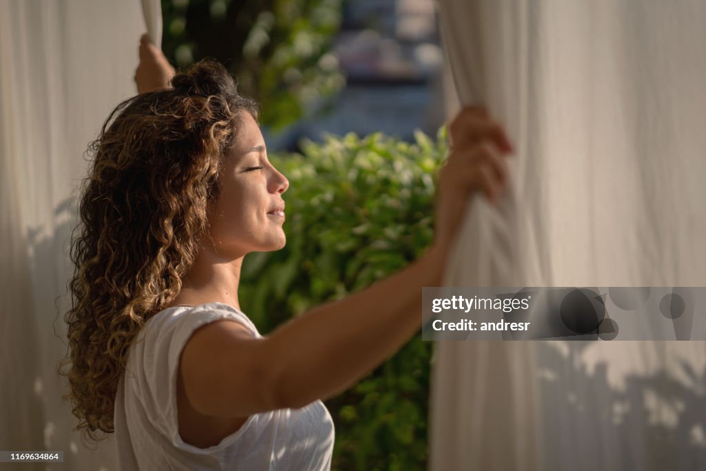 Mulher calma que olha através de seu indicador do quarto na manhã