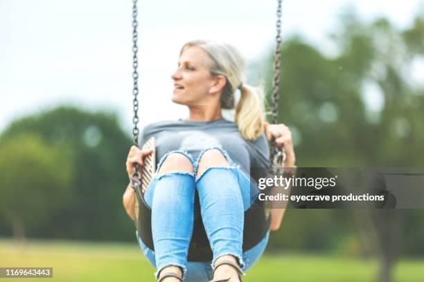 volwassen volwassen blond haar vrouwelijke vrouw met pony staart swingen op een swingset in een openbare park speeltuin - springfield missouri stockfoto's en -beelden