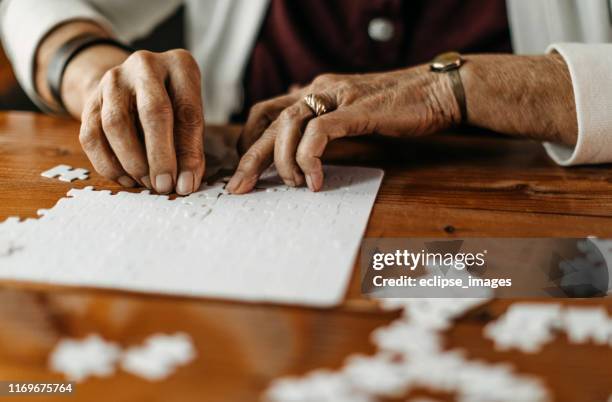 old woman playing puzzle game - senior puzzle stock pictures, royalty-free photos & images