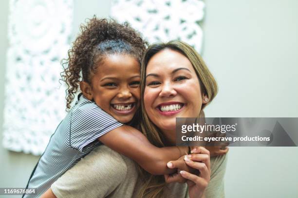 madre asiatica con figlia di etnia mista cinese e afroamericana a casa al chiuso in posa giocosa per ritratti sorridenti ed essere sciocchi - adoption foto e immagini stock