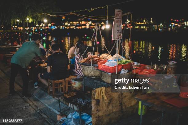 local hoi an hawker food with customer sitting at river bank at night enjoying the view while eating local cuisine - vietnam and street food stock pictures, royalty-free photos & images