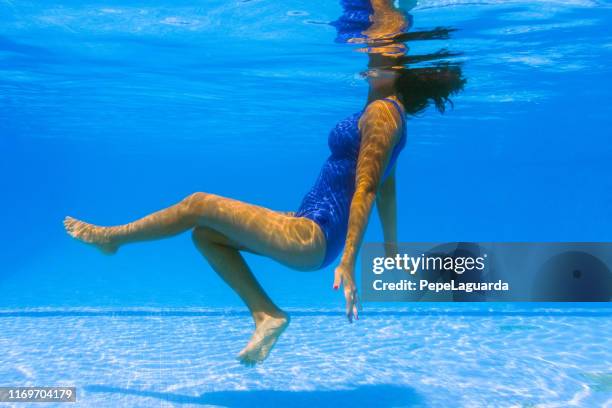 unterwasser-foto von einer eleganten jungen frau in einem blauen badeanzug entspannend - aquarobics stock-fotos und bilder
