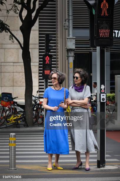 Fashion grandmas' models Wang Xinghuo and Sun Yang cross a street during a photo shooting on July 16, 2019 in Beijing, China. An online video about...