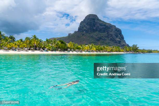 a tourist swimming in the turquoise sea in the le morne brabant peninsula, black river district, mauritius - mauritius beach stock-fotos und bilder