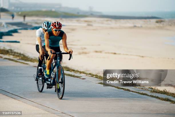 portrait of a blind triathlete together with his guide and their tandem bicycle - ciclismo tandem fotografías e imágenes de stock