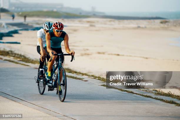 portrait of a blind triathlete together with his guide and their tandem bicycle - tandem bicycle foto e immagini stock