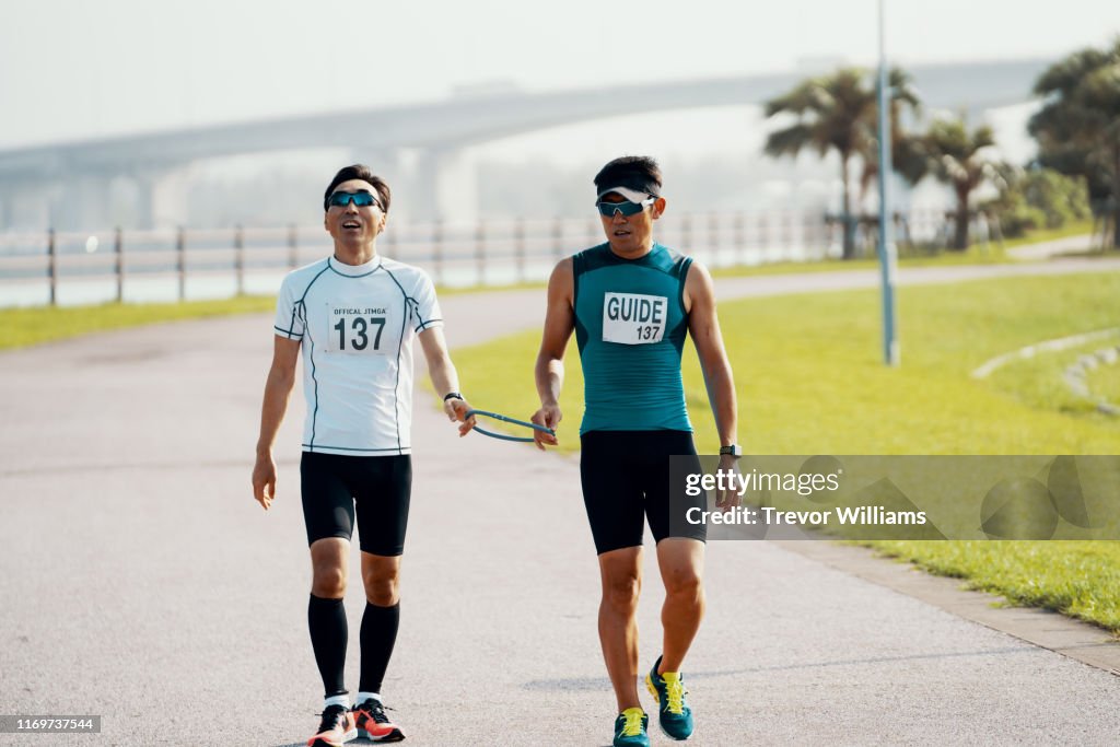 Blind triathlete and his guide walking before or after a triathlon event