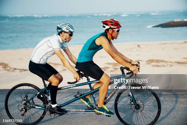 blind triathlete and his guide training on their tandem bicycle - bicycle tandem stock pictures, royalty-free photos & images