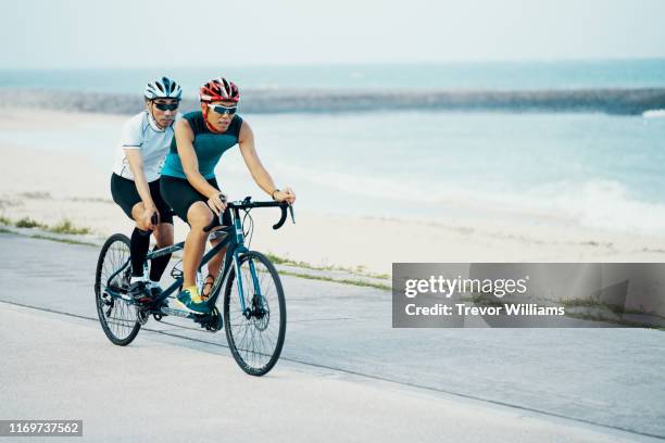 portrait of a blind triathlete together with his guide and their tandem bicycle - bicycle tandem stock-fotos und bilder
