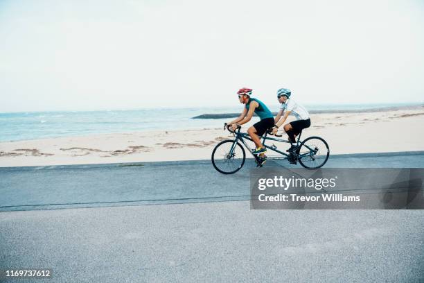 blind triathlete and his guide training on their tandem bicycle - tandem stock pictures, royalty-free photos & images