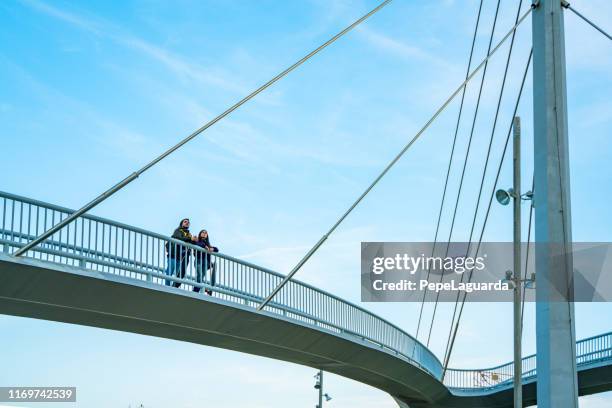 dos patinadores con sus longboards caminando en una pasarela elevada - puente colgante fotografías e imágenes de stock