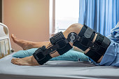 Asian woman patient with bandage compression knee brace support injury on the bed in nursing hospital.healthcare and medical support.