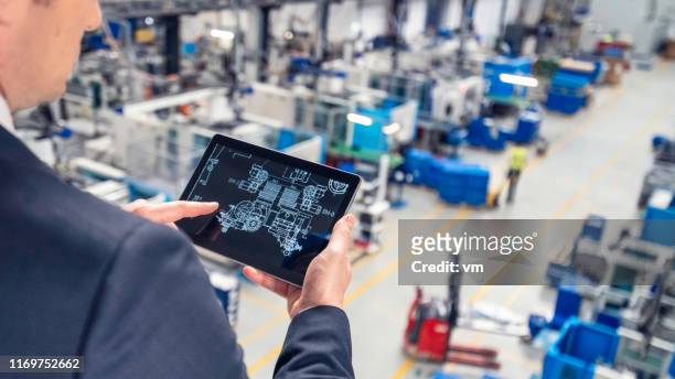 hombre usando tableta digital en una fábrica - remote controlled fotografías e imágenes de stock