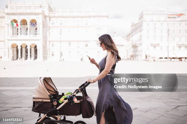 young mother walking a city with her baby - mother stroller stock pictures, royalty-free photos & images