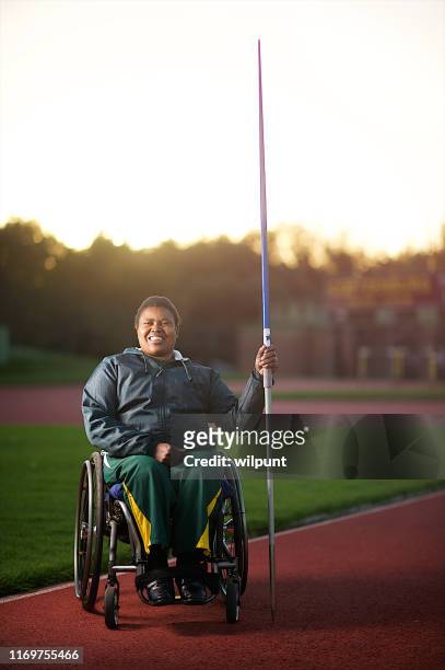 Disabled female javelin thrower in wheelchair in stadium smiling