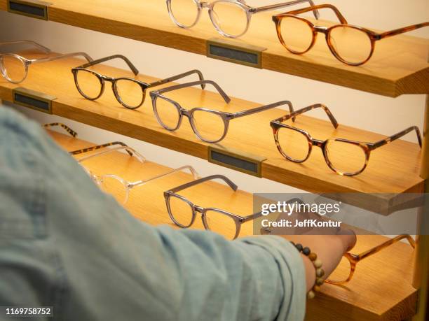 vrouw probeert op brillen - bril stockfoto's en -beelden